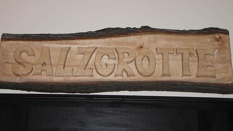 Über der Tür hängt eine hölzerne Tafel.