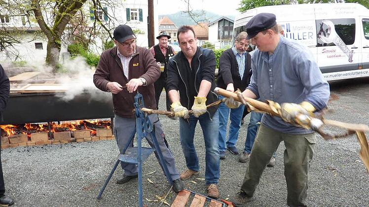 Viel Spaß hatten die Flößer beim kräftezehrenden Wiedendrehen. Links im Bild der mit Holz befeuerte Edelstahltrog, in dem die Haselnussruten und Fichtenstämmchen im kochenden Wasser "gebäht" wurden.  Foto: Gerd Fleischmann