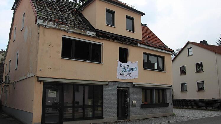 Von den Spuren des Brandes gekennzeichnet, steht das Gebäude auch noch vier Jahre nach dem Feuer in Johannisthal. Seit kurzem ist es mit einem Betttuch versehen, das die Aufschrift trägt: "Dieser Schandfleck muss weg". Fotos: Corinna Igler (2), Archiv (1)