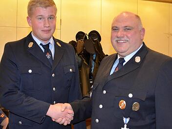 Erfolgreiche Jugendarbeit: Manuel Rost wird von Kommandant Bernd Müller symbolisch per Handschlag in den aktiven Feuerwehrdienst aufgenommen. Foto: Kathrin Kupka-Hahn
