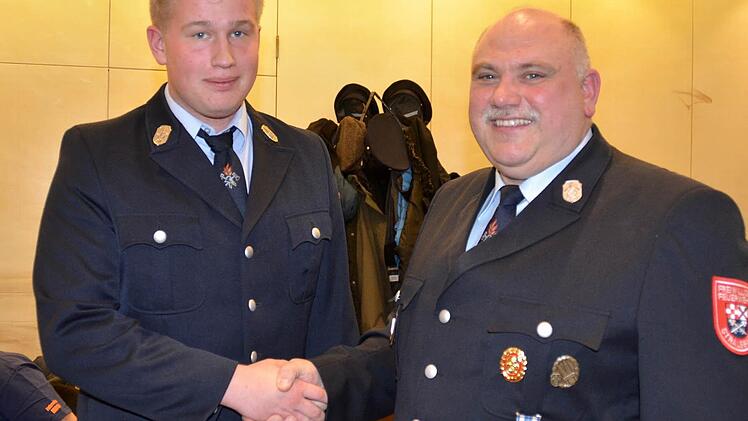 Erfolgreiche Jugendarbeit: Manuel Rost wird von Kommandant Bernd Müller symbolisch per Handschlag in den aktiven Feuerwehrdienst aufgenommen. Foto: Kathrin Kupka-Hahn