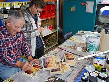 Werkstattmitarbeiter reinigen kleine Holzgemälde vor dem Verkauf am traditionellen Weihnachtsbasar. Foto: Sigismund von Dobschütz
