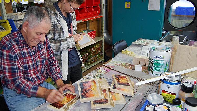 Werkstattmitarbeiter reinigen kleine Holzgemälde vor dem Verkauf am traditionellen Weihnachtsbasar. Foto: Sigismund von Dobschütz