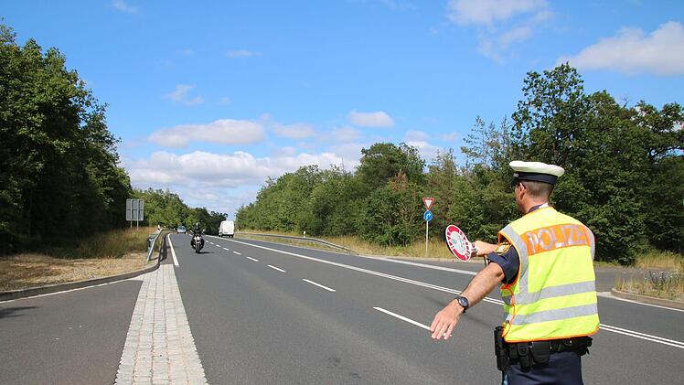Jochen Emmerling von der PI Bad Kissingen hält eine Motorradfahrerin auf den Parkplatz am Schindberg an. Thomas Malz