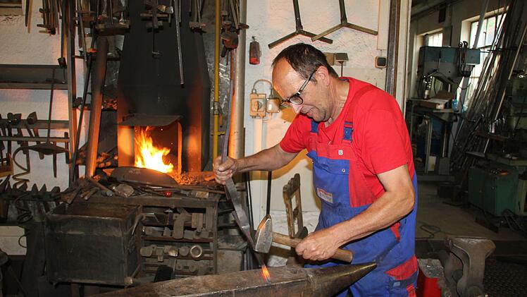 Der liebste Arbeitsplatz von Andreas Behrschmidt ist am Amboss in seiner Werkstatt. Gerade hat er ein glühendes Stück Eisen aus dem Feuer der Esse (hinten) geholt. Aus dem H-förmigen Abschnitt eines Doppel-T-Trägers entsteht ein kunstvolles Männchen.  Fotos: Friedwald Schedel