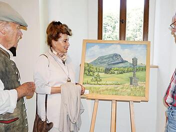 Herbert Schneider (rechts) zeigt derzeit 35 Bilder aus verschiedenen Epochen seiner Schaffensphasen im Bruder-Franz-Haus auf dem Kreuzberg. Gert Raimann und seine Frau Irene lassen sich vom Haselbacher Rhönmaler die Werke erläutern.  Foto: Marion Eckert