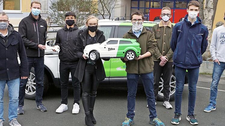 Seminarleiter Johannes Mann (von links), Schulleiter Thomas Carl, David Middrup (Entwicklungsingenieur im Bereich Driving Assistance Research bei Valeo) sowie sieben der neun Schüler des P-Seminars, Yusuf Firat, Anna-Lena Menzel, Johannes Vogel, Alexander Heß, Leon Sommer, Joshua Gunzelmann und Ernest Kulekin, präsentieren den Prototyp des autonom fahrenden Modells eines Range Rover Evoque.  Foto: Andreas Gagel