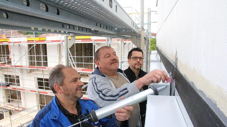Nysret Imrihari (von links) und Reiner Stühler von der Firma "Haga" dichten nach dem Einbau der mehr als 200 Fenster die Fassade des Landratsamtes ab. Architekt Stephan Scharf betreut die Arbeiten. Im Hintergrund der Rohbau des Erweiterungsbaus. Foto: Ralf Ruppert