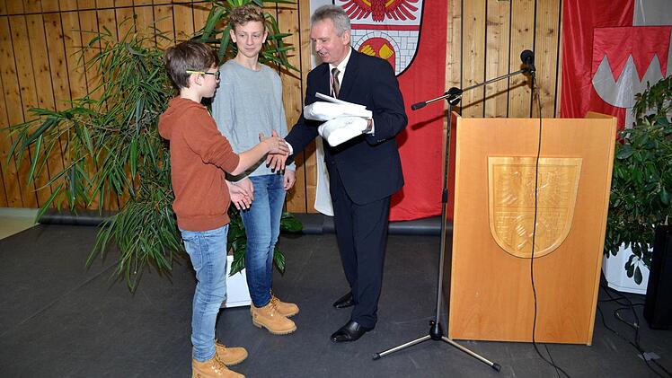 Bürgermeister Werner Diersch überreicht Valentin (links) und Lukas Kübrich ein Geschenk als Anerkennung für ihre hervorragenden Ergebnisse beim landesweiten Wettbewerb "Jugend forscht".