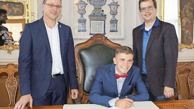 Mannschaftskapitän Marc Kunz trägt sich ins Goldene Buch der Stadt ein, rechts Bürgermeister Christian Lange, links Brose-Baskets-Geschäftsführer Rolf Beyer Foto: Riegerpress