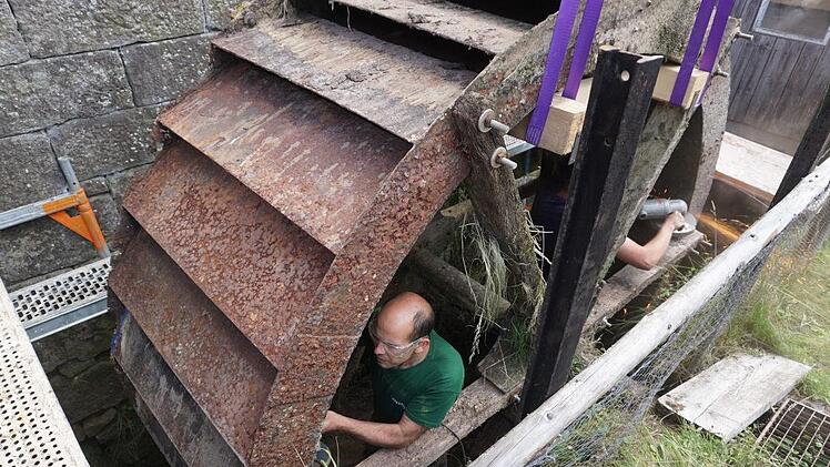 Bevor das Mühlrad aus dem Mühlgraben gehoben werden konnte, musste es in zwei Teile geschnitten werden. Das Bild zeigt Oliver Schwenzer bei der Arbeit. Foto: Marion Eckert