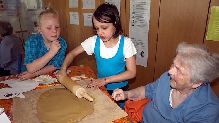 Nur noch ein wenig rollen, dann ist der Tonfladen groß genug. Zoe (links) und Maria zusammen mit Ottilie Schnappauf. Foto: Susanne Deuerling