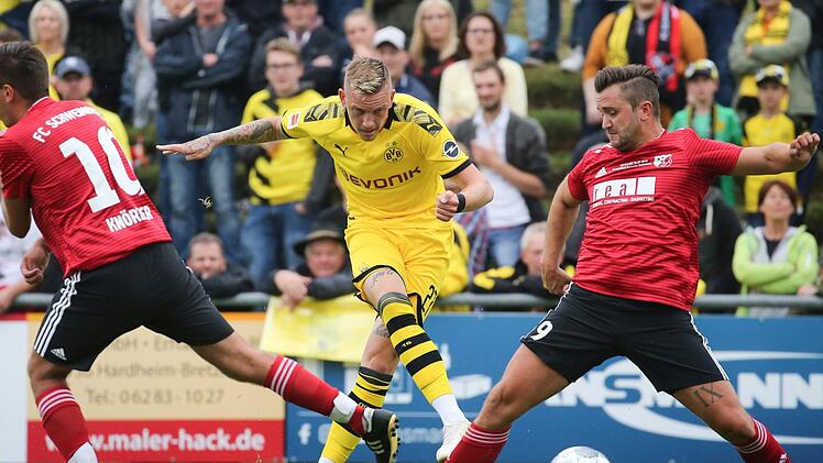 Dortmunds Marius Wolf (Mitte) setzt sich gegen die Kreisliga-Kicker des FC Schweinberg, Christoph Knörzer (links) und Andreas Michel, durch. Beim 10:0-Erfolg seines BVB erzielte der Einberger den Treffer zum 5:0.  Foto: Karl-Josef Hildenbrand/dpa