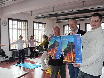 Während die Damen im Hintergrund sich bei Qi Gong entspannen, weisen (von links) Sebastian Schmidt, Bürgermeister Gerald Brehm und Thomas Reimer auf das neue Programmheft hin. Foto: Maria Leicht