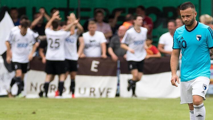 Während der SV Erlenbach (im Hintergrund) das 1:0 bejubelt, stapft Adem Selmani in Richtung Anstoßpunkt: Nach der 1:2-Niederlage im Rückspiel der Relegation zur Bayernliga bekommt die SpVgg Jahn Forchheim gegen den SC Feucht eine weitere Chance. Das Hinspiel findet heute um 18.30 Uhr in Forchheim statt.  Foto: Sportfoto Zink