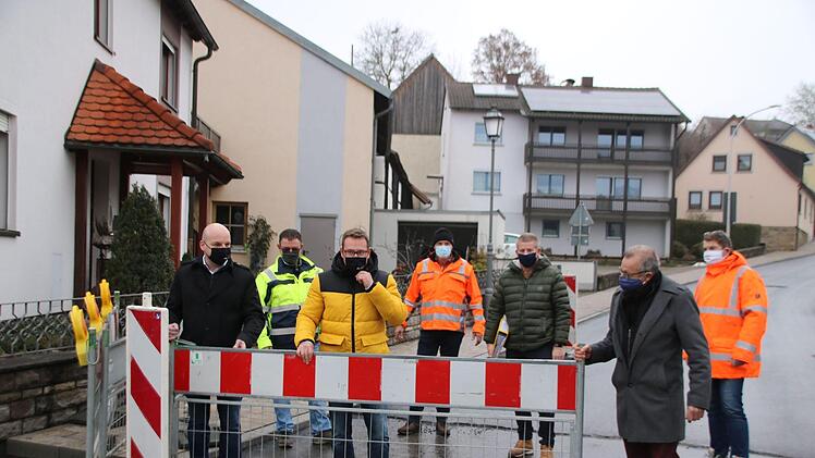 Bürgermeister Michael Kastl, Martin Holland-Nell (Abwasserverband Saale-Lauer), Ortssprecher Fabial Nöth, August Ullrich (Ullrich-Bau) Oberbauleiter Steffen Kiesel, stellvertretender Landrat Emil Müller und Bauleiter Markus Wehner räumen schon mal probeweise die Absperrung weg. Foto: Thomas Malz