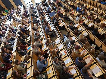 Studenten sitzen bei der Erstsemesterbegrüßung am Campus Koblenz der Universität Koblenz-Landau im großen Hörsaal. Foto: Thomas Frey/dpa