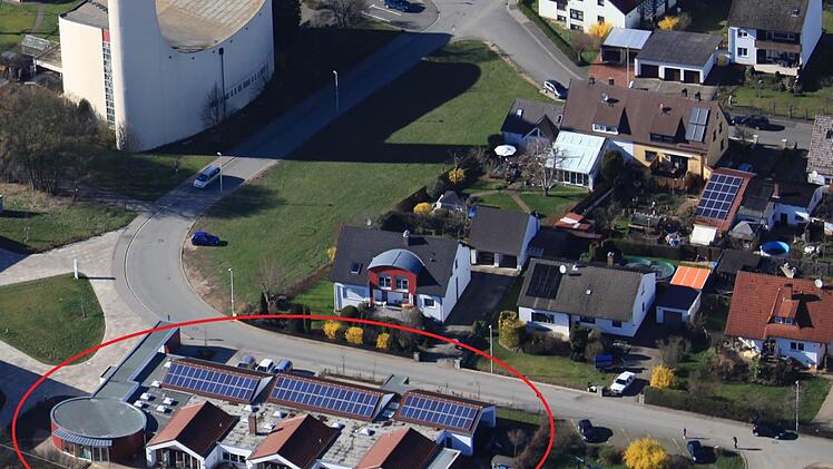 An den rechten Teil des bestehenden Kindergartens (roter Kreis) wird das neue Gebäude angebaut. Um die weitere Bauleitplanung umsetzen zu können, benötigt die Gemeinde das in Privatbesitz befindliche Areal gegenüber der Kirche (grüne Fläche). Luftbild: Adolf Nüßlein