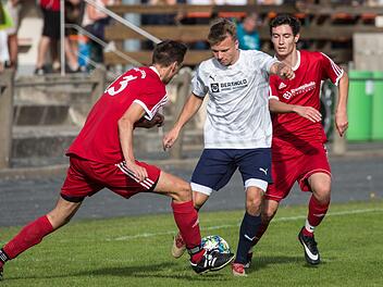 Zwischen den beiden Wei&szlig;enbrunnern Sebastian Buckreuss und Jonas Wich (rote Trikots, v.l.) sucht der Obermainer Dominique Pinter eine L&uuml;cke, um den Ball abspielen zu k&ouml;nnen.  Foto: Heinrich Wei&szlig;