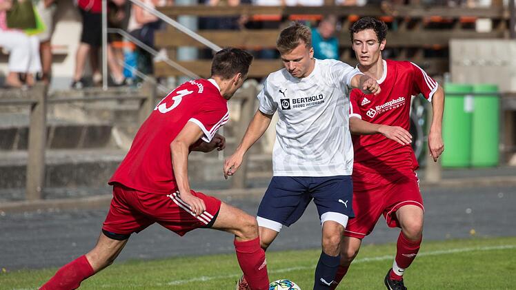 Zwischen den beiden Wei&szlig;enbrunnern Sebastian Buckreuss und Jonas Wich (rote Trikots, v.l.) sucht der Obermainer Dominique Pinter eine L&uuml;cke, um den Ball abspielen zu k&ouml;nnen.  Foto: Heinrich Wei&szlig;