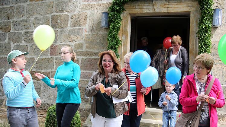 Luftballons und Zettel, auf die alle Gottesdienstbesucher gute Wünsche für die Zukunft Bischwinds schreiben konnten, hatte Pfarrer Tobias Knötig vorbereitet. Auch Lektorin und Festausschussvorsitzende Petra Grell (Bildmitte) freute sich über die Idee. Foto: Bettina Knauth
