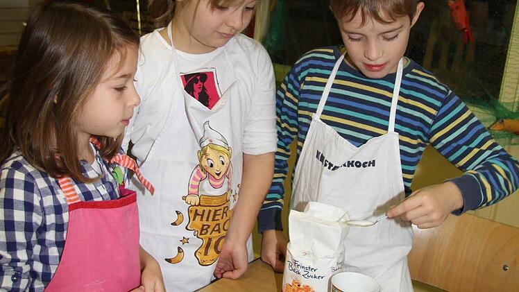 Für einen Tassenkuchen messen Emilia Reinl, Angelina Seling und Emil Vießmann tassenweise die Zutaten ab.