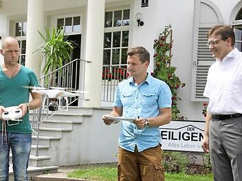 Eine kleine Drohne filmt gleich den"Heiligenhof" von oben: Kameramann Stephan de Leuw (links) steuert sie, Regisseur Kilian Reichert (Mitte) gibt die Kommandos und Hausherr Steffen Hörtler staunt. Die maximale Flugzeit: knapp zehn Minuten. Fotos: Edgar Bartl