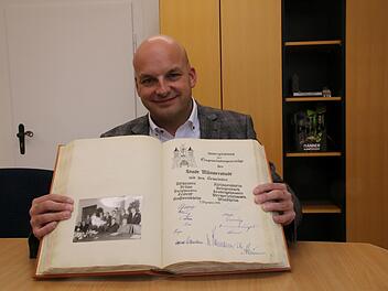 Bürgermeister Michael Kastl zeigt den Eintrag im Goldenen Buch der Stadt Münnerstadt. Vor 50 Jahren unterzeichneten die Bürgermeister der umliegenden Gemeinden den Eingliederungsvertrag und verewigten sich im Goldenen Buch. Foto: Thomas Malz