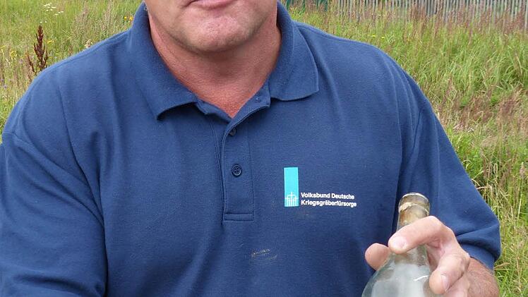 Umbetter Uwe Lemke mit einer Grabflasche aus dem Jahr 1942