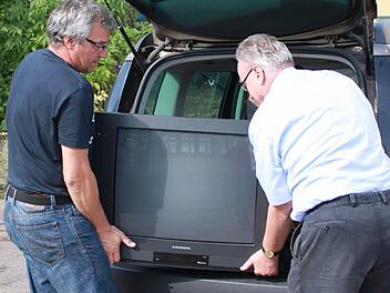 Gemeinsam laden Franz-Josef Zeheter (r.) und Thomas Schmitt den alten Fernseher aus. Foto: Katharina Becht