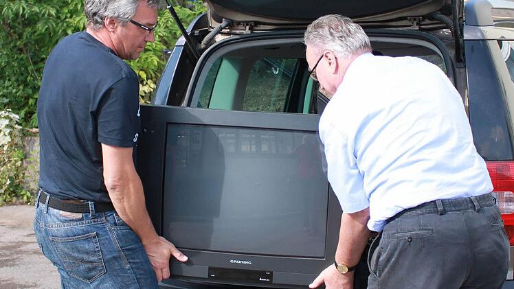 Gemeinsam laden Franz-Josef Zeheter (r.) und Thomas Schmitt den alten Fernseher aus. Foto: Katharina Becht