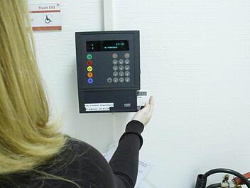 Eine Mitarbeiterin zieht ihre Karte durch die elektronische Zeiterfassung. In kleinen Firmen ersetzt Vertrauen die Stechuhr. Foto: Josef Hofbauer