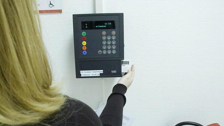 Eine Mitarbeiterin zieht ihre Karte durch die elektronische Zeiterfassung. In kleinen Firmen ersetzt Vertrauen die Stechuhr. Foto: Josef Hofbauer