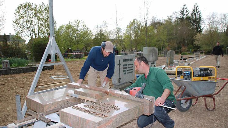 Steinmetz Alexander Kessler (rechts) misst mit einem Mitarbeiter die Abstände für ein passgenaues Aufstellen der Grabsteine. Foto: Heike Beudert