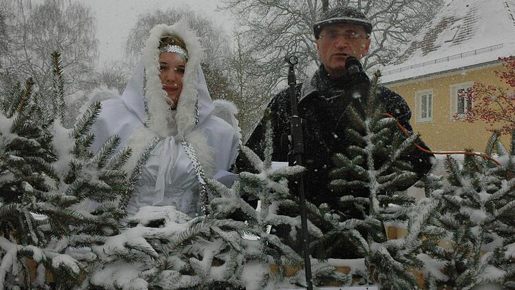 Bürgermeister Wilhelm Schneider mit dem Christkind Desiree Büschel hinter Tannenspitzen. Fotos: Gerhard Schmidt