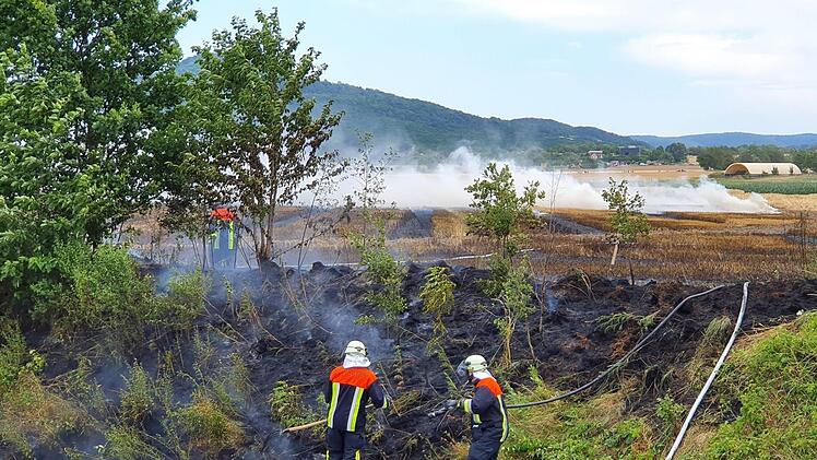 Feuerwehrleute bei den Löscharbeiten am Samstag am Bahndamm nahe Unterzettlitz. Das in Brand geratene Feld grenzt an die Bahnlinie an.Rolf Hollering