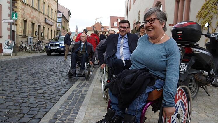 Norbert Knobel (VdK Untererthal) und Bürgermeister Armin Warmuth testen einmal selbst das Pflaster rund um das Rathaus. Maria Nürnberger, die seit ihrer Geburt auf einen Rollstuhl angewiesen ist, führt sie an. Foto: Arkadius Guzy