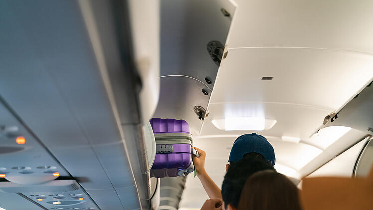 Hand take off hand luggage. Bag cabin on top shelf in airplane Lufthansa Handgep&auml;ck Kabinenkoffer Economy Basic Tarif Gep&auml;ck Fluggesellschaft Airline Kurz- und Mittelstrecke Spartarif Laptop-Tasche Rucksack Freigep&auml;ck Billigflieger Aufgabegep&auml;ck Reisen Flug Passagiere Tarif&auml;nderung Miles More Verbraucherschutz Geb&uuml;hren Sitzplatzreservierung Umbuchung Bordverpflegung Vielfliegerprogramm Austrian Airlines Swiss Brussels Airlines Eurowings Lufthansa Group