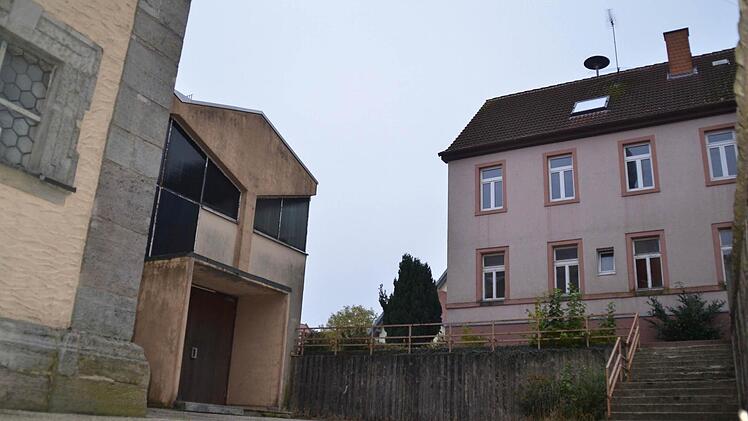 Die Gebäude an der Kirche stehen nah beieinander: Rechts ist die alte Schule zu sehen, links die alte Pfarrkirche mit dem Anbau St. Pius. Dieser soll ebenso wie die Mauer zur Kirche abgerissen werden. Außerdem soll an der alten Kirche ein Anbau Richtung Schule entstehen. Foto: Kathrin Kupka-Hahn