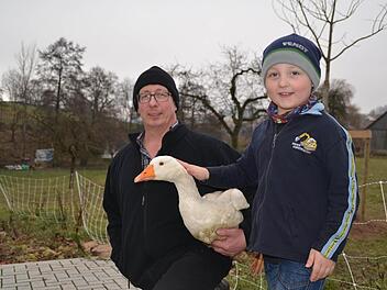 Landwirt Gerald Heinle liebt Gänse. Mit ihnen hat er vor 25 seinen Betrieb aufgebaut. Hier hält er eine ganz gewöhnliche Hausgans auf dem Arm, die sein Sohn Arne streichelt.  Foto: Kathrin Kupka-Hahn