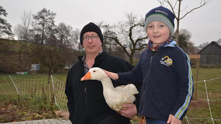 Landwirt Gerald Heinle liebt Gänse. Mit ihnen hat er vor 25 seinen Betrieb aufgebaut. Hier hält er eine ganz gewöhnliche Hausgans auf dem Arm, die sein Sohn Arne streichelt.  Foto: Kathrin Kupka-Hahn
