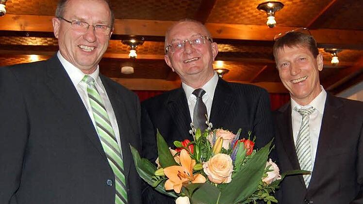 Pfarrgemeinderatsvorsitzender Helmut Kießling (links) und Kirchenpfleger Hubert Gehrlich (rechts) überreichen dem Jubilar einen prächtigen Blumenstrauß.