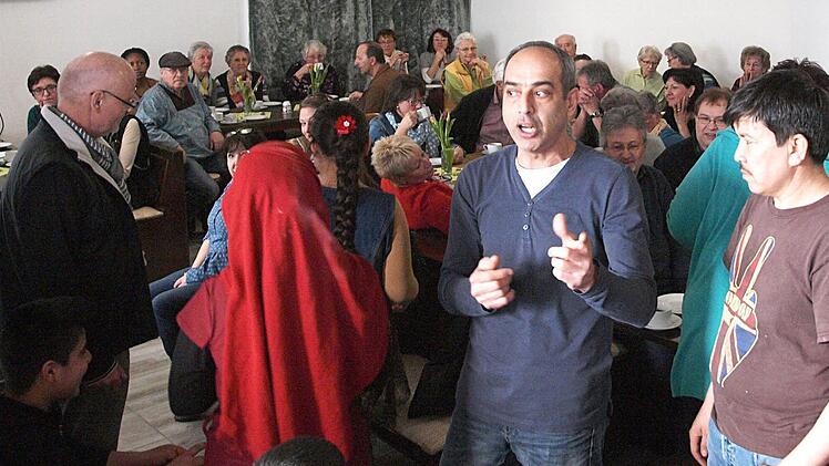 Renza (Bildmitte), vor mehr als 30 Jahren aus dem Iran nach Deutschland gekommen, überwindet als Übersetzer die Sprachbarriere am Wochenende im früheren Grenzgasthof. Das Interesse und auch die Neugier der Einwohner von Fürth amBerg an den 39 Flüchtlingen ist groß. Foto: Christoph Winter