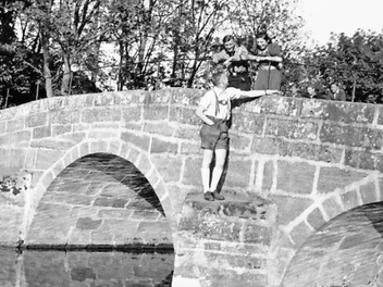 Über die Alster in Memmelsdorf führte früher eine Steinbrücke mit drei Bögen. Sie ist längst von der Bildfläche verschwunden. Das Bild aus dem Jahr 1942 zeigt auf der Brücke im Gespräch mit jungen Männern Agnes Zeuner, die Tochter des einstigen Forstbüttners.  Archivfoto: Arnold Deininger