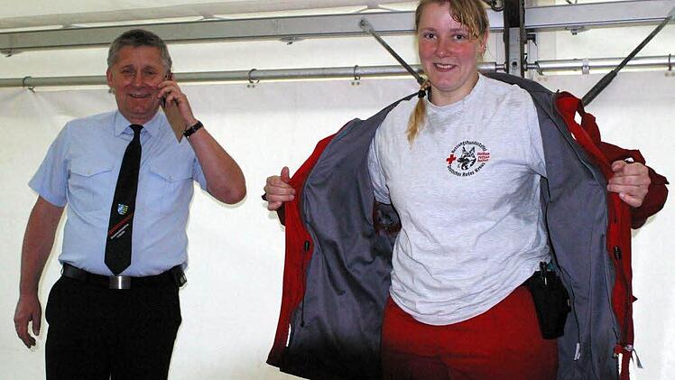 Regenjacken für die Hundestaffel fordert Annette Reißenweber angesichts ihres nassen T-Shirts, während sich Kreisbrandrat Manfred Lorenz am Telefon über die aktuelle Situation im Landkreis informiert.