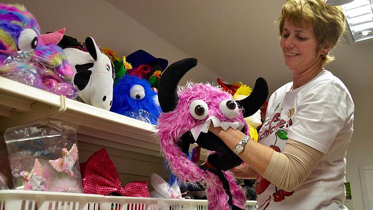 Nicht nur ausgefallene Kostüme gibt es in Großenbrach, sondern auch lustige Kopfbedeckungen, wie dieses Monster hier, das Mitarbeiterin Gudrun Lochner ins Regal räumt. Foto: Kathrin Kupka-Hahn