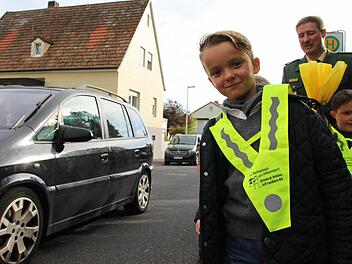 Erstklässler Heinrich Oppermann (vorne) wartet mit Verkehrserzieher Matthias Kleren (hinten) an der Bushaltestelle der Henneberg Grundschule in Garitz. Foto: Benedikt Borst