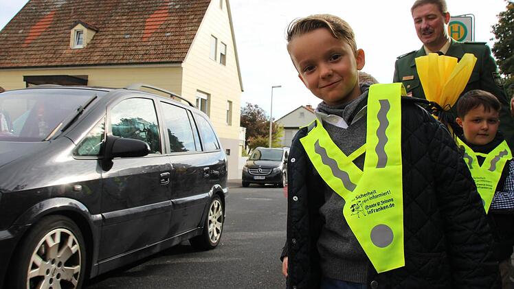 Erstklässler Heinrich Oppermann (vorne) wartet mit Verkehrserzieher Matthias Kleren (hinten) an der Bushaltestelle der Henneberg Grundschule in Garitz. Foto: Benedikt Borst