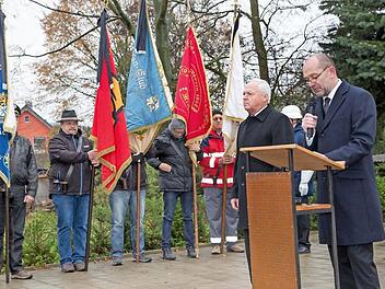 Bürgermeister Helmut Fischer und Dekan Johannes Grünwald riefen zum Gedenken an die Toten der beiden Weltkriege auf. Im Hintergrund die Fahnenabordnungen der Michelauer Vereine.  Foto: Klaus Gagel