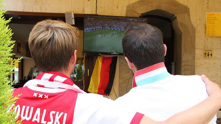 Zwischen Schoko-Becher und Espresso fiebert "Coco" (rechts) mit seinen Gästen mit. Deutsche Fan-Utensilien dürfen da nicht fehlen. Foto: Ulrike Müller